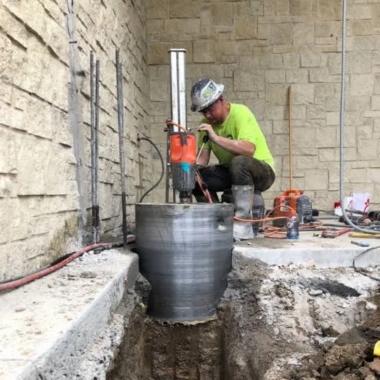 Operator carrying out a core drilling operation on a concrete wall